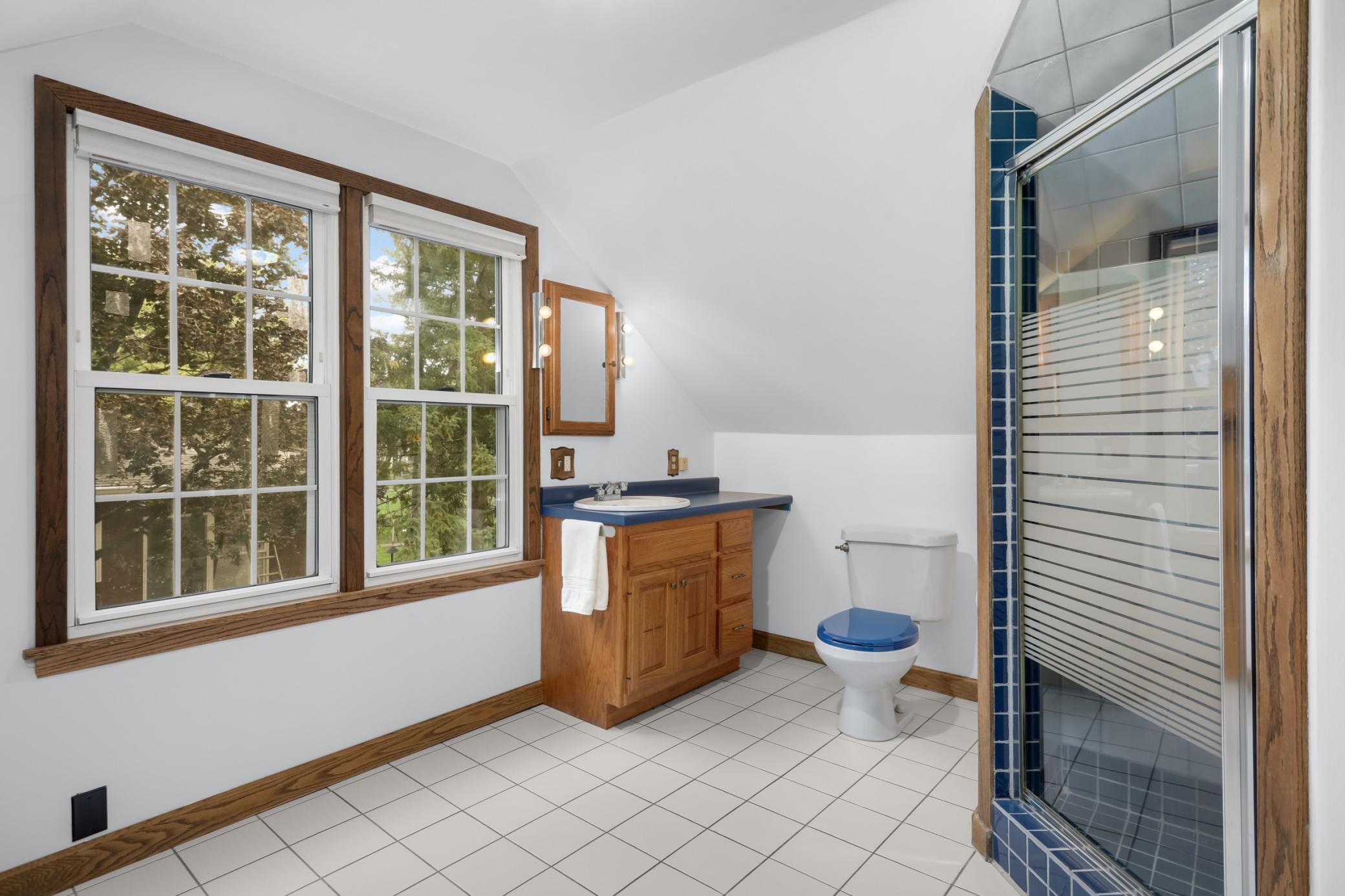 This spacious bathroom has a full ceramic tile shower, and enough space to double as a dressing room.