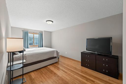 The generously sized primary bedroom features beautiful bamboo flooring and neutral tones, creating a warm and relaxing retreat.