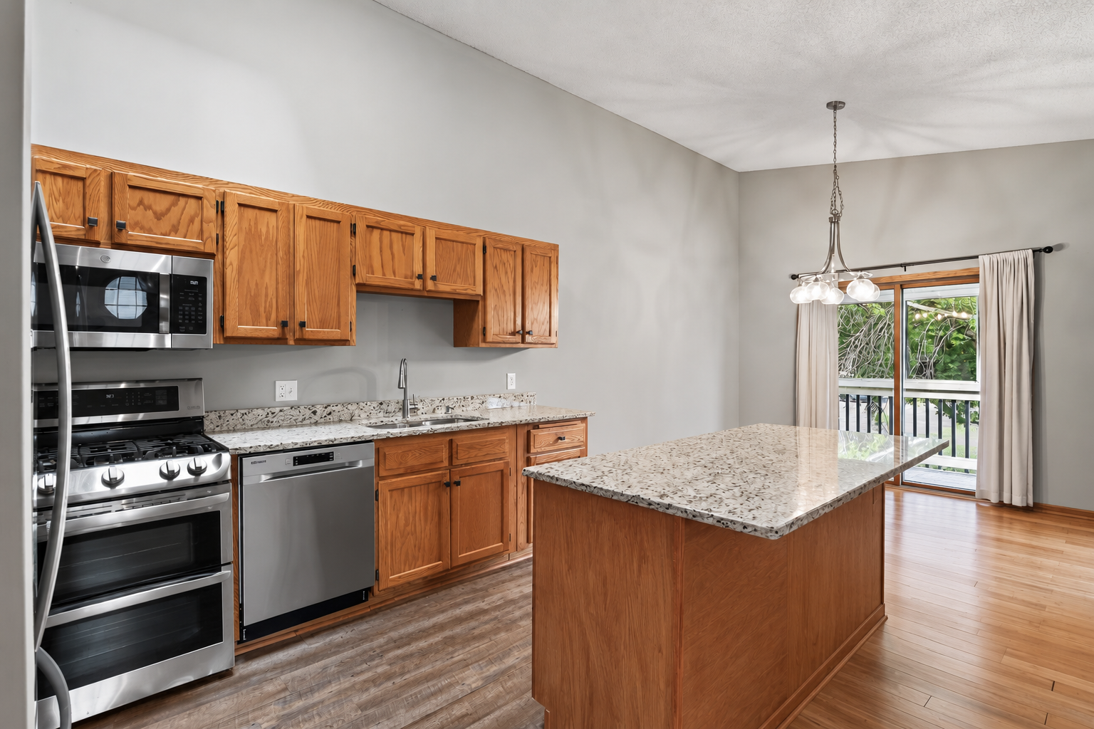 The kitchen features rich wood cabinetry, granite countertops, and stainless steel appliances.