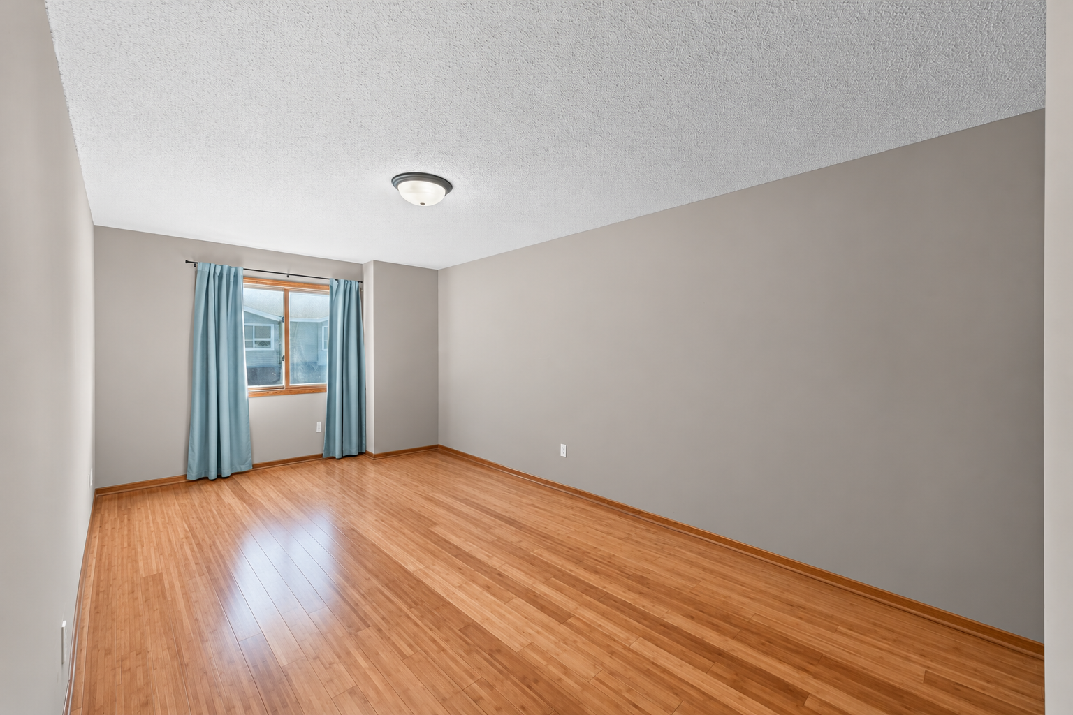 The generously sized primary bedroom features beautiful bamboo flooring and neutral tones, creating a warm and relaxing retreat.