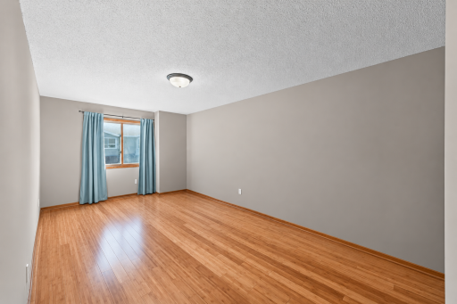 The generously sized primary bedroom features beautiful bamboo flooring and neutral tones, creating a warm and relaxing retreat.