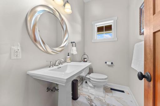 A look at the main-level half bathroom, featuring tile floors and a classic pedestal sink.