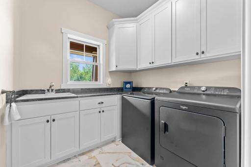 Conveniently located off the kitchen, the main-level laundry room features cabinetry, countertops, and a sink, along with a spacious 7x4 walk-in pantry/storage closet with shelving.