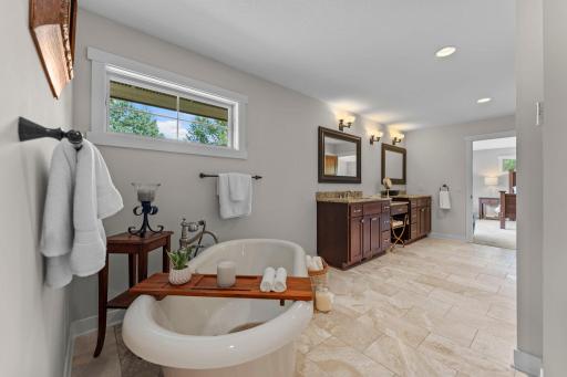 The private ensuite offers comfortable heated floors, a dual vanity, a spa-like oversized soaking tub, and a large tiled walk-in shower with dual shower heads.