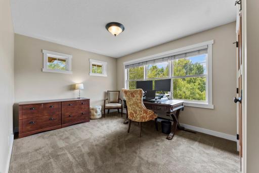 Bedroom four on the upper level features carpeting and large windows, creating the perfect versatile space for a bedroom, home office, or flex room.