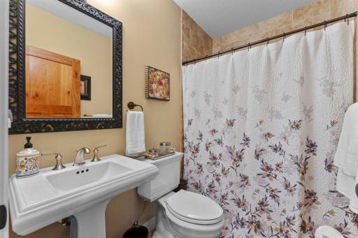 A nearby ¾ bathroom features a walk-in tile shower and single vanity.