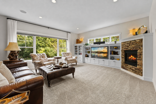 The main-level living room offers carpeting, an expansive picture window, a built-in entertainment center and shelving, and a gas-burning fireplace.