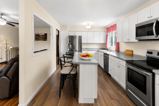 Another great view of the updated kitchen showcasing stainless steel appliances, abundant white cabinetry, generous countertop space, and a large center island perfect for casual dining, entertaining with family and friends!