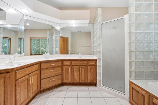 The primary bath has lots of cabinet space, huge vanity top with 2 separate sinks, and a unique glass block shower surround