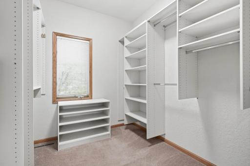 The primary walk in closet has nice organizers and a window for natural light