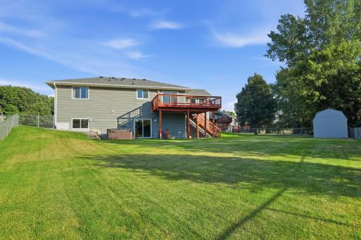 Backyard view of the home, deck, patio, and hot tub