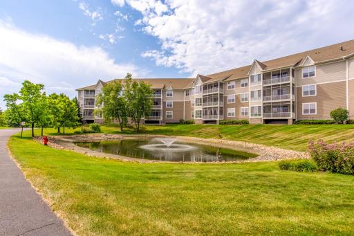 Picturesque Medina Ridge grounds feature a scenic pond with fountain, expansive green space, and walking paths.