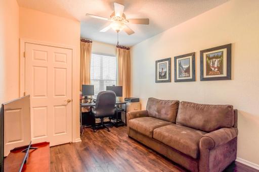 Comfortable second bedroom offers LVP flooring, a ceiling fan, a bright window, and flexible space for a home office or sitting area.