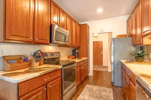Gourmet galley-style kitchen features stainless-steel appliances, abundant cabinetry, generous counter space, and LVP flooring.