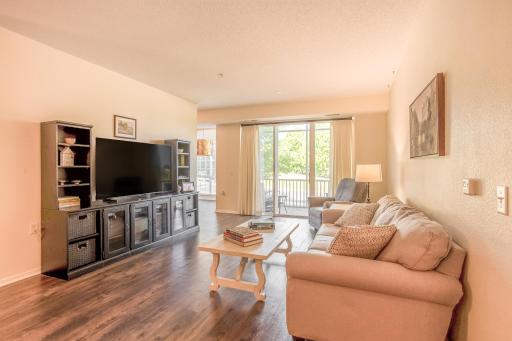 Bright walkout living room features LVP flooring, 9' vaulted ceilings, and direct access to the screened-in porch.