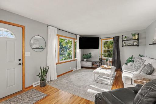 Bright main living room with large front windows and hardwood floors.