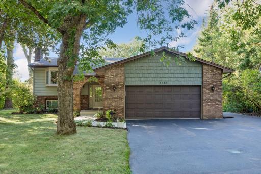 Another look at the exterior highlighting the earthy green shake siding accents, timeless brickwork, and extra wide asphalt driveway.