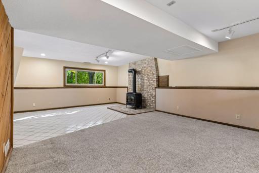 Yet another perspective of the lower level family room, highlighting the brick hearth with free-standing gas stove and the plush, comfortable carpeting.