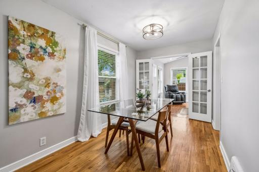 Dining area with hardwood floors and French doors leading to the sunroom.