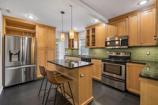 Center-island kitchen with abundant cabinetry, slate floors, and stainless steel appliances.