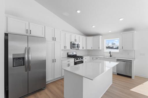 (Photo of similar home, actual finishes may vary) Designed for adventurous cooks, the well-equipped kitchen showcases extensive flat panel cabinetry for ample storage room, gleaming quartz countertops and cutting-edge features to simplify mealtimes.