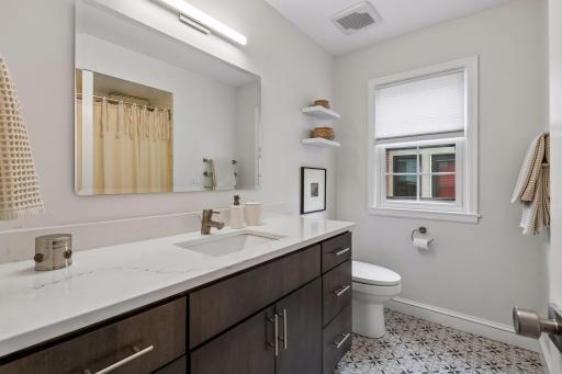 Lovely main level full bathroom with stone countertops and fresh tile