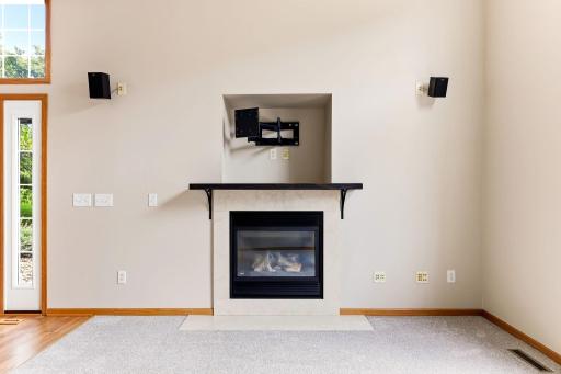 A tiled gas fireplace with a dark wood mantel anchors the living room, and the recessed niche above is already wired and mounted for your TV.