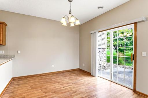 Sunlight spills across laminate floors in the dining area, where a five-light chandelier and sliding patio doors make every meal feel bright and easy.
