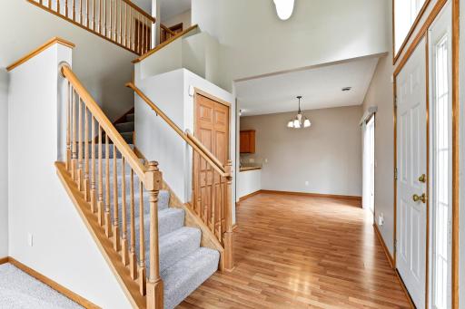 Oak spindles and a carpeted staircase lead to the upper level, with an open view from the two-story foyer into the dining room.