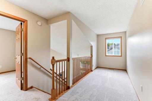 A sunny loft at the top of the stairs makes an easy home office, reading nook, or play space, with its own window and a railing overlooking the entry below.