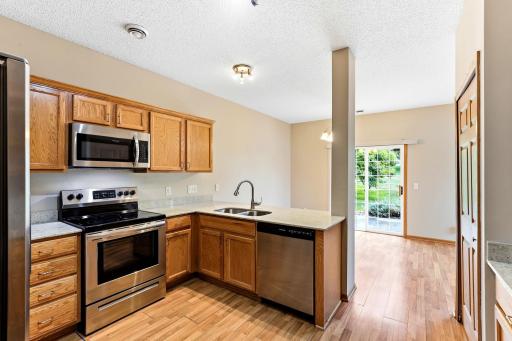A stainless range, dishwasher, and microwave line the kitchen, and the peninsula sink faces the dining area so the cook stays part of the conversation.