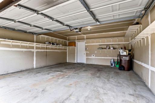 Built-in shelving lines the garage walls, keeping bins, tools, and gear off the floor so both cars fit with room to spare.