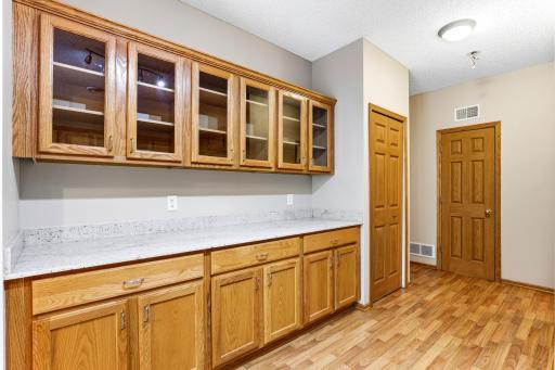 Glass-front cabinets and a long granite counter create a built-in hutch and serving station just off the kitchen. Ideal for coffee, cocktails, or extra storage.
