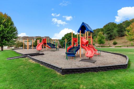 Open green space and a second play structure back up to a tree-lined hillside, giving everyone room to roam right in the neighborhood.