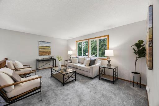 Upstairs, the spacious living room features a railing overlooking the dining area below, a large rear-facing window allowing for abundant natural light, and brand-new carpeting that extends throughout.