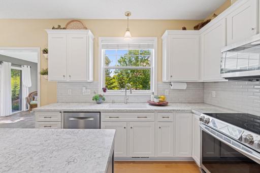 Crisp white shaker cabinetry, two-tone accents, tile backsplash, and stainless steel appliances.