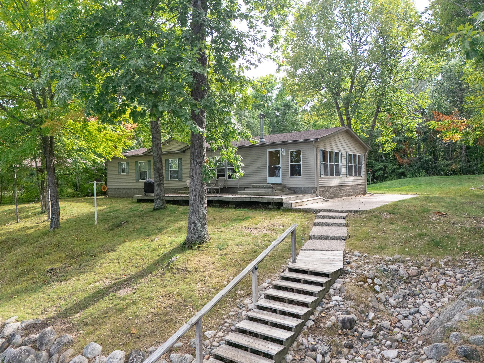 Lakeside deck with stone patio/steps leading to wood steps and railing