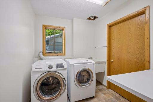 Main floor laundry with Samsung washer and Bosch gas dryer. Built-in folding table, set tub and window-make this space both useful and inviting.