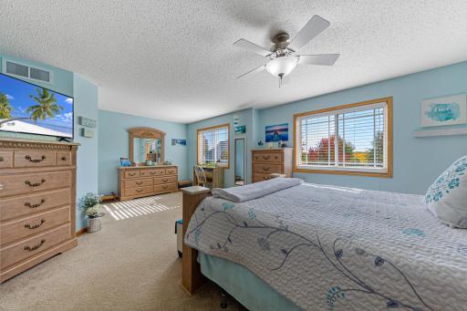 Large primary bedroom with ceiling fan and two windows
