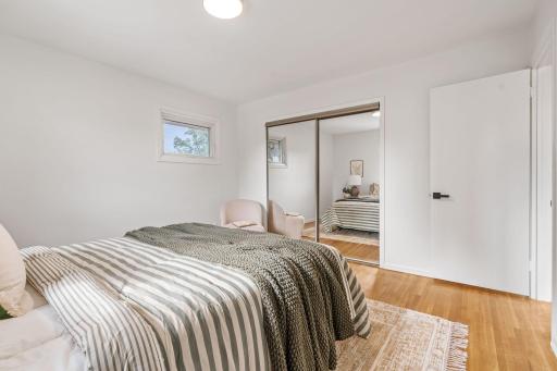 The bedroom includes warm hardwood floors, clean neutral finishes, and a spacious mirrored closet for convenient storage.