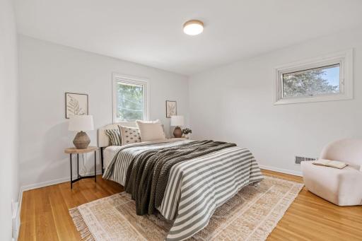 Upper level primary bedroom features beautiful hardwood floors, neutral finishes, and multiple windows that bring in plenty of natural light.