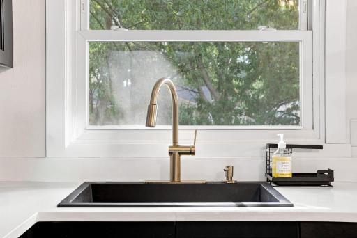 Matte-black deep stone sink accented with elegant gold hardware gives the kitchen a sophisticated contrast.