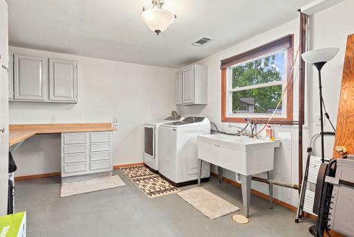 The NEW large, updated laundry room features a brand-new washer and dryer, a double utility sink, generous counter space, and abundant storage.