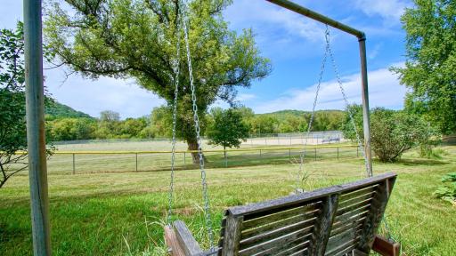 Enjoy stunning sunset views right from your swing, with the added charm of watching local ball games just beyond your own backyard.