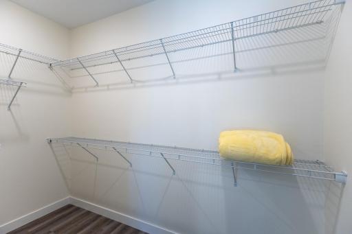 Walk-in primary closet with extensive shelving and storage.