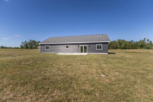 Rear exterior view showing the home's simple one-level design and open backyard.