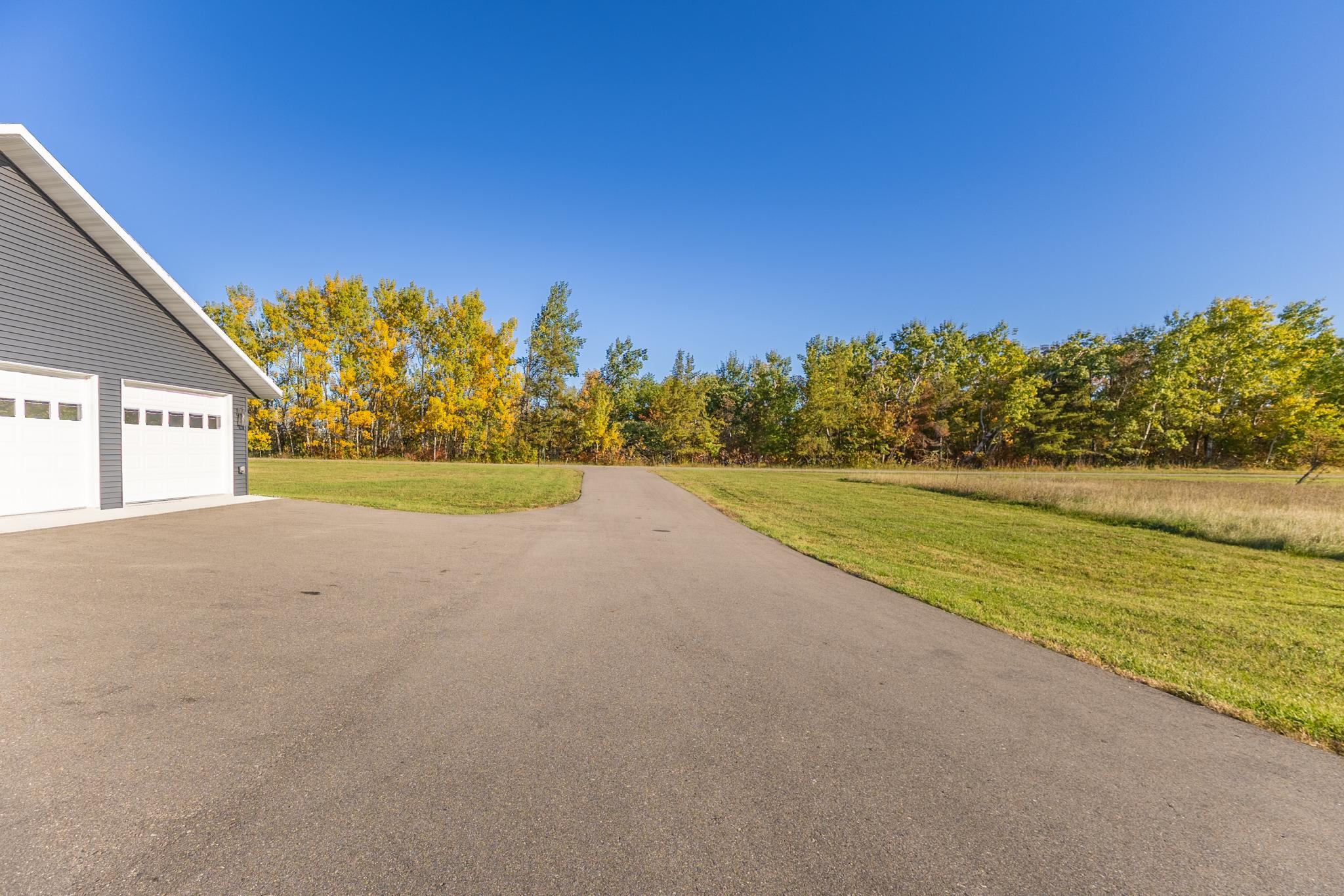 Paved driveway with a wooded backdrop and convenient access to the home and shop.