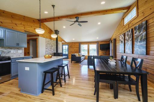 Wonderfully-open floor plan with log rail walls, hickory hardwood flooring, and new lighting. Two pendants hang above the island, and the NEW quartz countertops are dressed up with a tile backsplash.