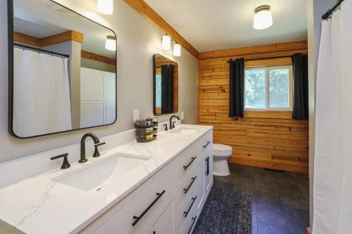 The main floor FULL bathroom just underwent a FULL RENOVATION and includes NEW LVP flooring, NEW tub/shower combo, a SOLID WOOD, elevated-height vanity with dual sinks and quartz countertops, NEW lighting, linen storage, toilet, trim and paint!