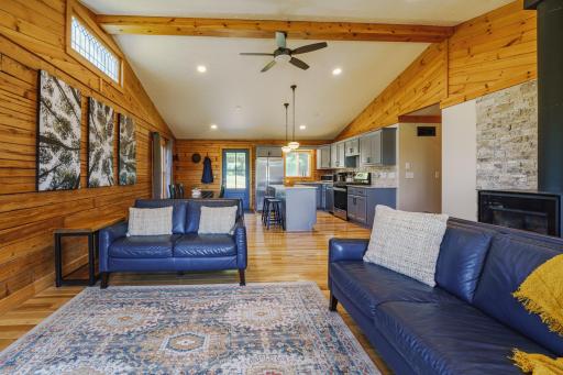 Inviting and warm interior with log walls, fresh ceiling paint, updated lighting, and a new stone accent wall behind the woodstove.